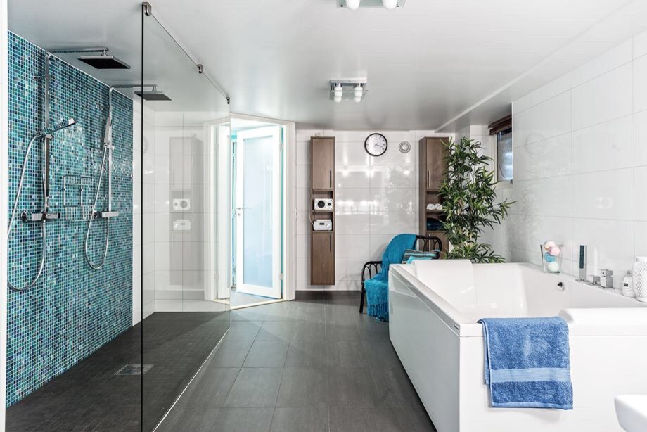 Bild på ett funkis badrum med dusch, med släta luckor, skåp i mellenmörkt trä, en jacuzzi, en dubbeldusch, blå kakel, vit kakel, mosaik, vita väggar, grått golv och med dusch som är öppen