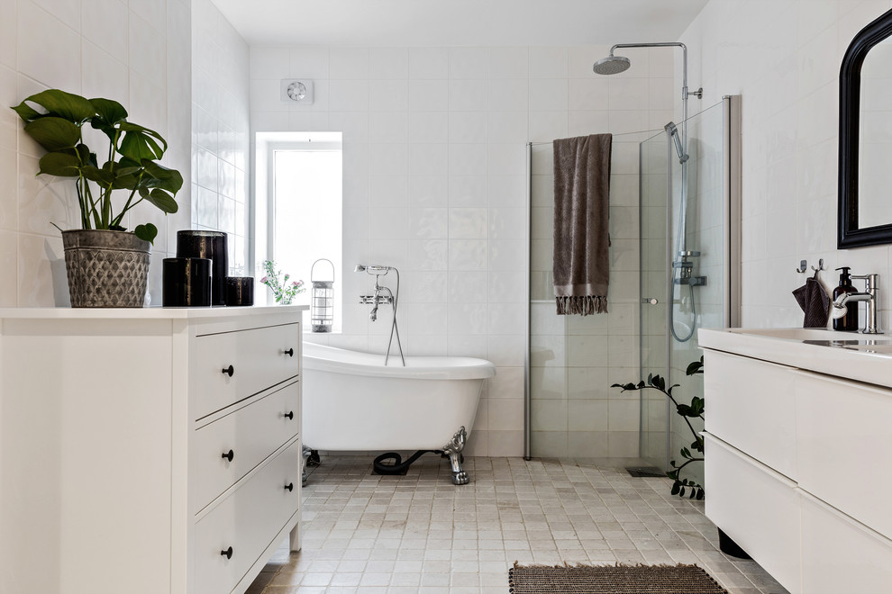 Aménagement d'une salle de bain principale scandinave avec un placard à porte plane, des portes de placard blanches, une baignoire sur pieds, une douche d'angle, un carrelage blanc, un mur blanc, un sol beige et une cabine de douche à porte battante.