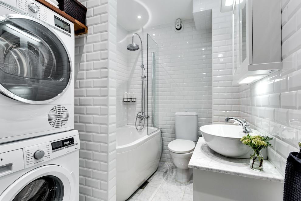 Inredning av ett modernt mellanstort badrum med dusch, med en dusch/badkar-kombination, en toalettstol med hel cisternkåpa, grå kakel, porslinskakel, marmorgolv, ett fristående handfat och marmorbänkskiva