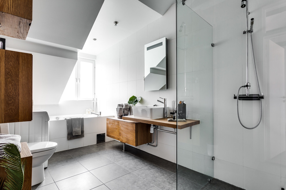 Large minimalist 3/4 white tile and porcelain tile walk-in shower photo in Stockholm with medium tone wood cabinets, a one-piece toilet, white walls, a vessel sink and wood countertops