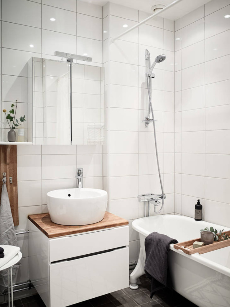 Inspiration för skandinaviska badrum med dusch, med släta luckor, vita skåp, en dusch/badkar-kombination, vit kakel, träbänkskiva, ett badkar med tassar, ett fristående handfat, grått golv och dusch med duschdraperi