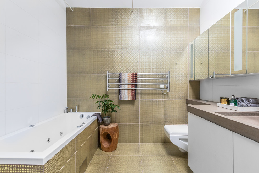 Inspiration för mellanstora moderna brunt badrum, med släta luckor, vita skåp, en dusch/badkar-kombination, en vägghängd toalettstol, beige kakel, gul kakel, ett platsbyggt badkar, vita väggar och gult golv