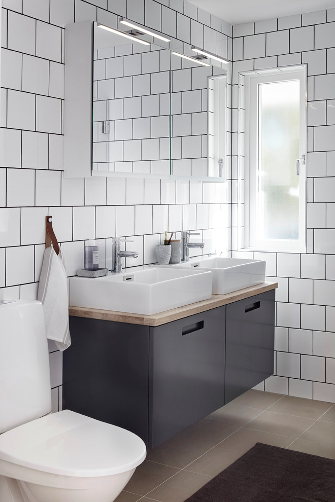 Foto på ett stort funkis badrum, med släta luckor, grå skåp, vit kakel, porslinskakel, vita väggar, ett fristående handfat och träbänkskiva