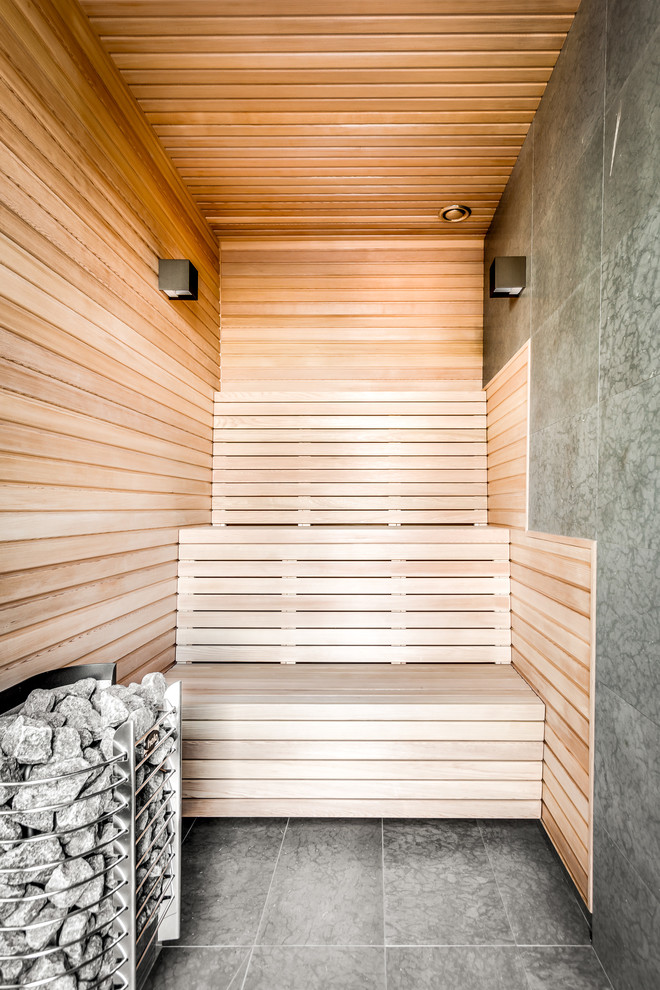 Diseño de sauna actual con baldosas y/o azulejos grises, paredes marrones y suelo gris