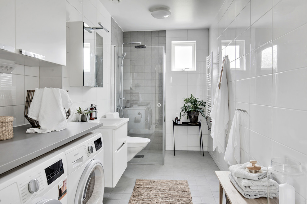 Idéer för ett mellanstort modernt badrum med dusch, med släta luckor, vita skåp, en hörndusch, en vägghängd toalettstol, grå kakel, vit kakel, porslinskakel, ett väggmonterat handfat, laminatbänkskiva, grått golv och dusch med gångjärnsdörr