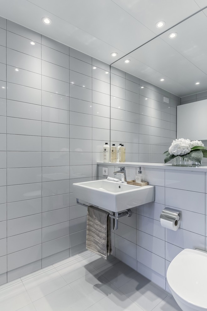 Immagine di una stanza da bagno padronale moderna con piastrelle grigie e lavabo sospeso