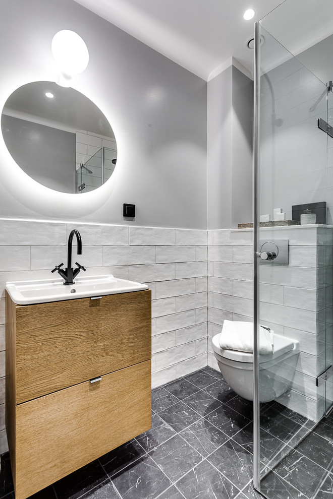 Réalisation d'une salle d'eau nordique en bois clair de taille moyenne avec un placard à porte plane, une douche à l'italienne, WC suspendus, un carrelage blanc et un mur gris.