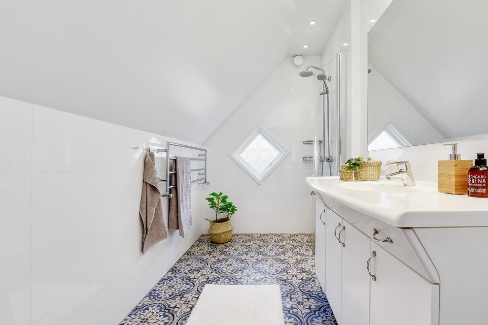 Diseño de cuarto de baño escandinavo con armarios con paneles lisos, puertas de armario blancas, ducha a ras de suelo, baldosas y/o azulejos blancos, paredes blancas, aseo y ducha, lavabo tipo consola, suelo azul, ducha abierta y encimeras blancas
