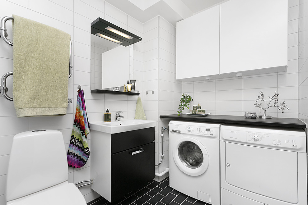 Foto på ett mellanstort funkis badrum, med svarta skåp, en toalettstol med separat cisternkåpa, ett väggmonterat handfat, släta luckor, keramikplattor, vita väggar, klinkergolv i keramik och vit kakel