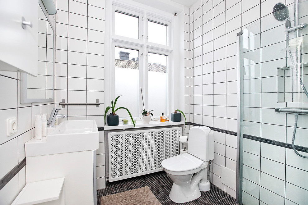 На фото: ванная комната среднего размера в современном стиле с угловым душем, раздельным унитазом, черной плиткой, белой плиткой, белыми стенами, душевой кабиной, монолитной раковиной и керамогранитной плиткой с