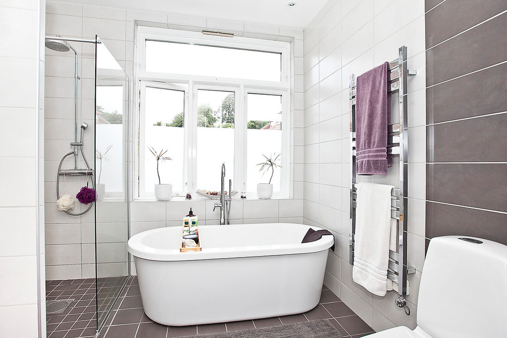 Exempel på ett stort modernt en-suite badrum, med ett fristående badkar, en kantlös dusch, en toalettstol med separat cisternkåpa, grå kakel, vit kakel, vita väggar, keramikplattor och klinkergolv i keramik