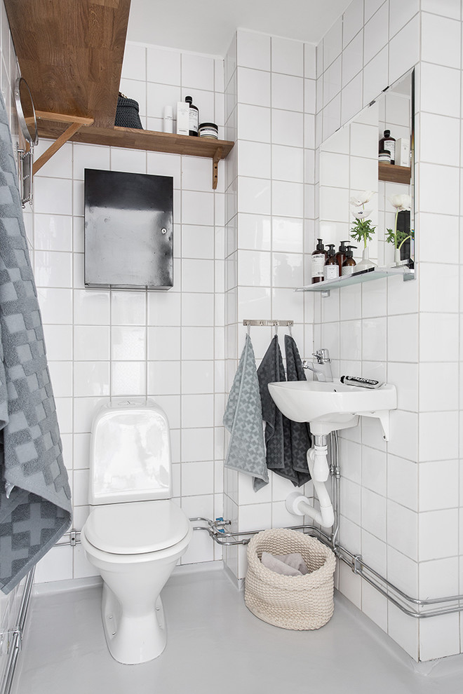 Mittelgroßes Nordisches Badezimmer mit Wandtoilette mit Spülkasten, Porzellanfliesen, weißer Wandfarbe, Sockelwaschbecken und grauem Boden in Göteborg