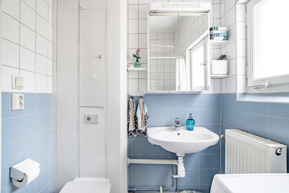 На фото: ванная комната в скандинавском стиле с плоскими фасадами, белыми фасадами, инсталляцией, синей плиткой, белой плиткой, синими стенами, душевой кабиной, подвесной раковиной и шторкой для ванной с