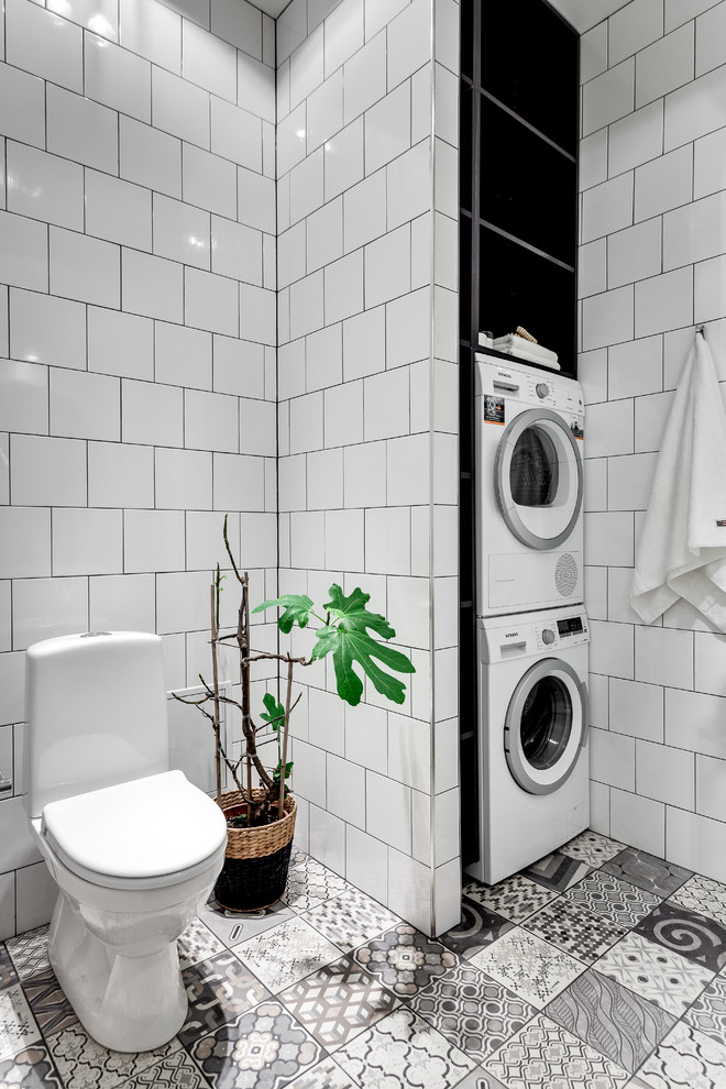 Mittelgroßes Nordisches Badezimmer mit Wandtoilette mit Spülkasten, weißer Wandfarbe, offenen Schränken, Keramikfliesen, Porzellan-Bodenfliesen und Wäscheaufbewahrung in Stockholm