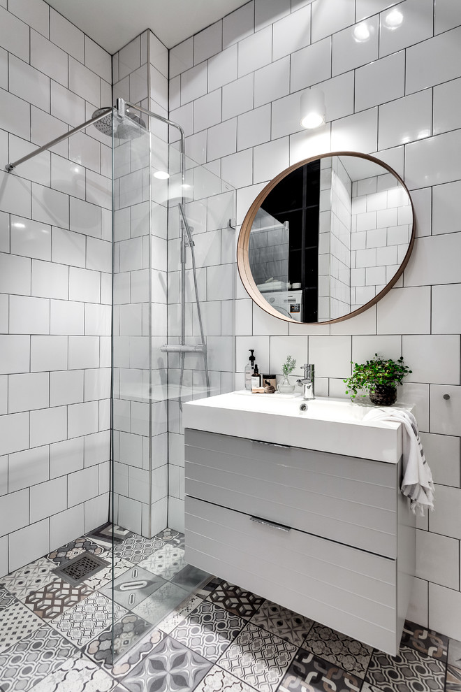 ストックホルムにある高級な中くらいな北欧スタイルのおしゃれなバスルーム (浴槽なし) (フラットパネル扉のキャビネット、グレーのキャビネット、バリアフリー、白いタイル、白い壁、セラミックタイルの床、セラミックタイル、オープンシャワー) の写真
