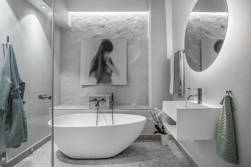 Imagen de cuarto de baño actual de tamaño medio con armarios abiertos, puertas de armario blancas, bañera exenta, paredes blancas y lavabo suspendido