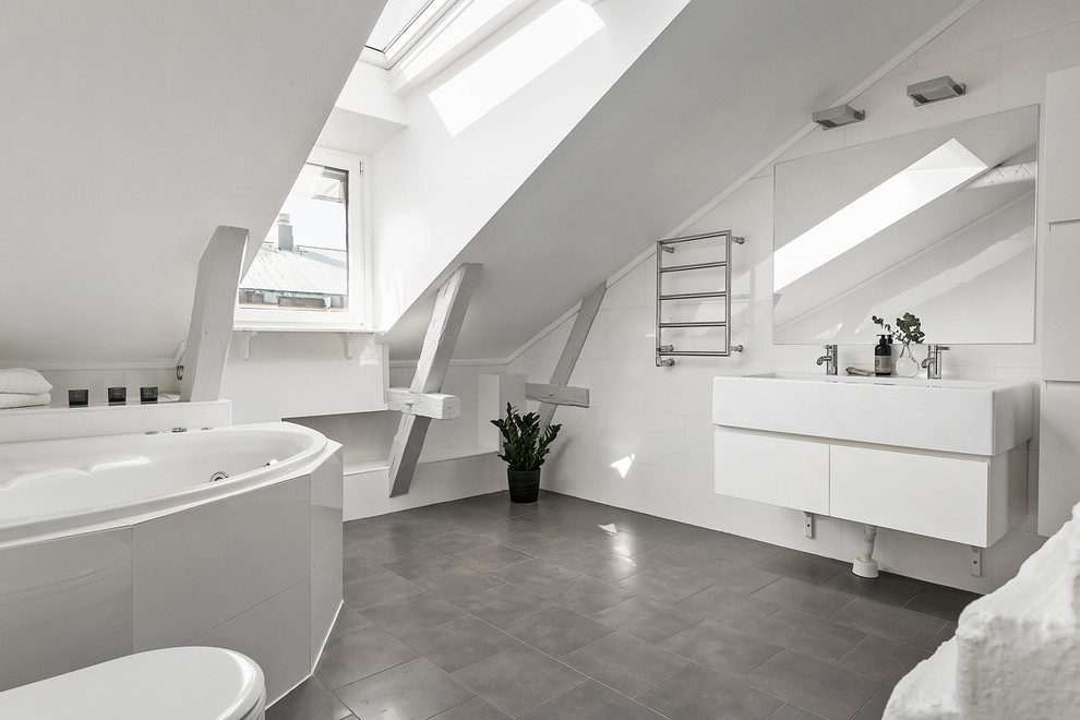 Idées déco pour une grande salle de bain scandinave avec un placard à porte plane, des portes de placard blanches, une baignoire d'angle, un mur blanc, un sol en carrelage de céramique et un lavabo intégré.