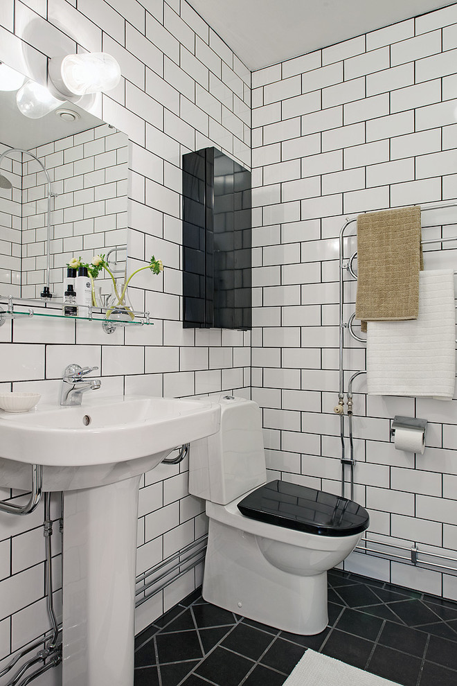 Nordisk inredning av ett mellanstort badrum med dusch, med svart och vit kakel, tunnelbanekakel, vita väggar, en toalettstol med separat cisternkåpa och ett piedestal handfat