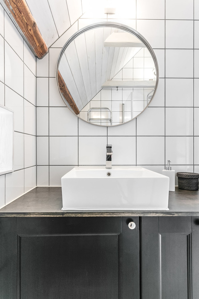 Réalisation d'une petite salle de bain nordique avec un placard avec porte à panneau encastré, des portes de placard noires, un mur blanc et un lavabo intégré.