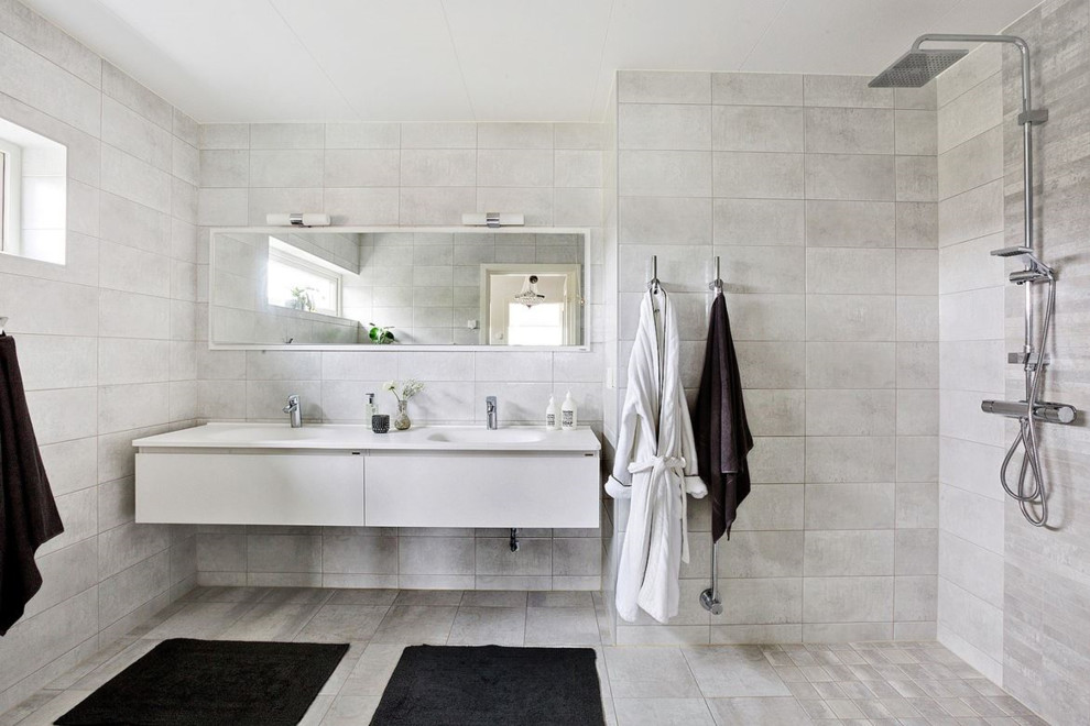 Cette image montre une grande salle d'eau minimaliste avec un placard à porte plane, des portes de placard blanches, une douche ouverte et un carrelage gris.