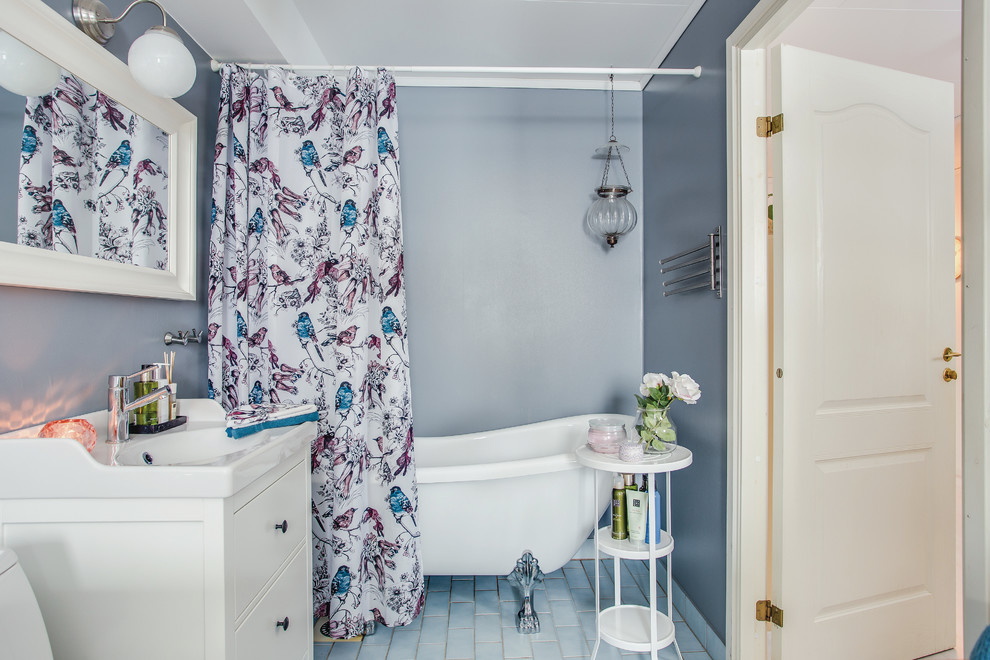 Shabby chic-inspirerad inredning av ett badrum, med släta luckor, vita skåp, ett fristående badkar, blå väggar, ett nedsänkt handfat, blått golv och dusch med duschdraperi