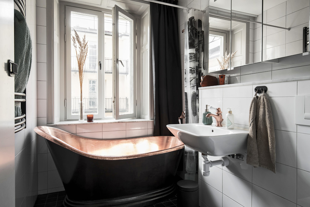 Diseño de cuarto de baño nórdico con bañera exenta, combinación de ducha y bañera, baldosas y/o azulejos blancos, lavabo suspendido y ducha con cortina