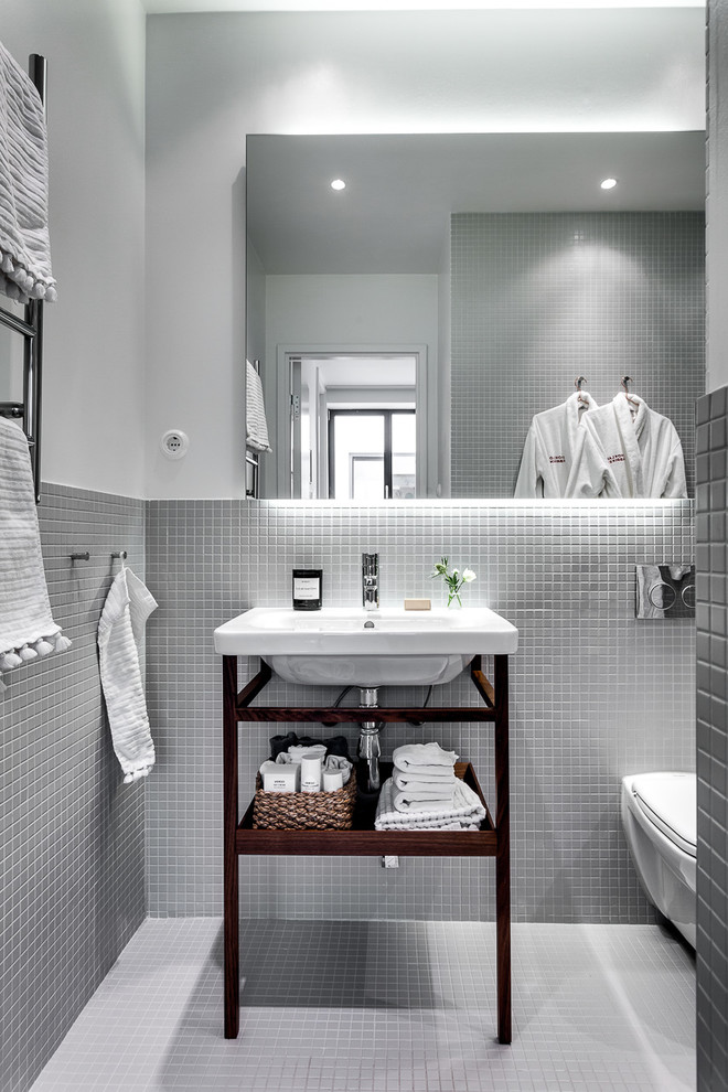 ストックホルムにある高級な中くらいな北欧スタイルのおしゃれな浴室 (オープンシェルフ、濃色木目調キャビネット、壁掛け式トイレ、グレーの壁、モザイクタイル、壁付け型シンク、モザイクタイル) の写真