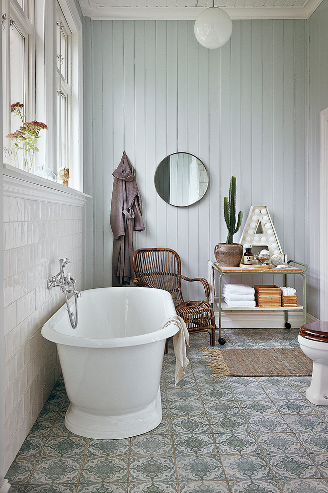 Inredning av ett lantligt mellanstort en-suite badrum, med öppna hyllor, ett fristående badkar, flerfärgad kakel, blå väggar, en toalettstol med hel cisternkåpa, porslinskakel, klinkergolv i keramik och träbänkskiva