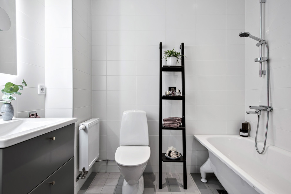 Inredning av ett modernt badrum, med släta luckor, svarta skåp, vit kakel, vita väggar och grått golv
