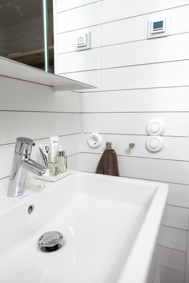 Badezimmer mit flächenbündigen Schrankfronten, türkisfarbenen Schränken, weißen Fliesen, weißer Wandfarbe und Trogwaschbecken in Stockholm