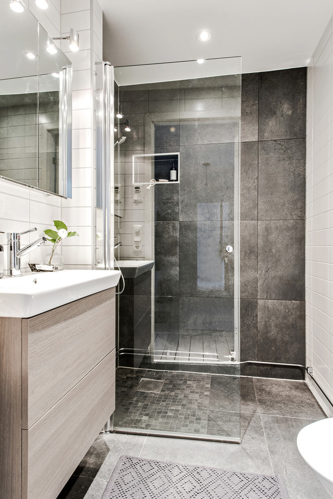 This is an example of a small contemporary shower room bathroom in Gothenburg with flat-panel cabinets, light wood cabinets, a corner shower and a built-in sink.