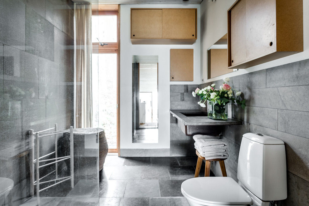 Exempel på ett stort industriellt badrum med dusch, med släta luckor, skåp i ljust trä, en toalettstol med hel cisternkåpa, grå väggar, betonggolv, ett nedsänkt handfat och bänkskiva i betong