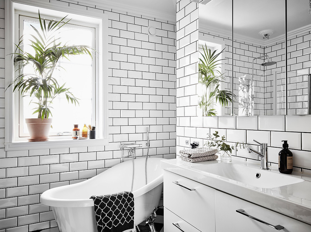 Inspiration for a scandi ensuite bathroom in Gothenburg with flat-panel cabinets, white cabinets, a claw-foot bath, a corner shower, metro tiles, white walls, an integrated sink and a hinged door.