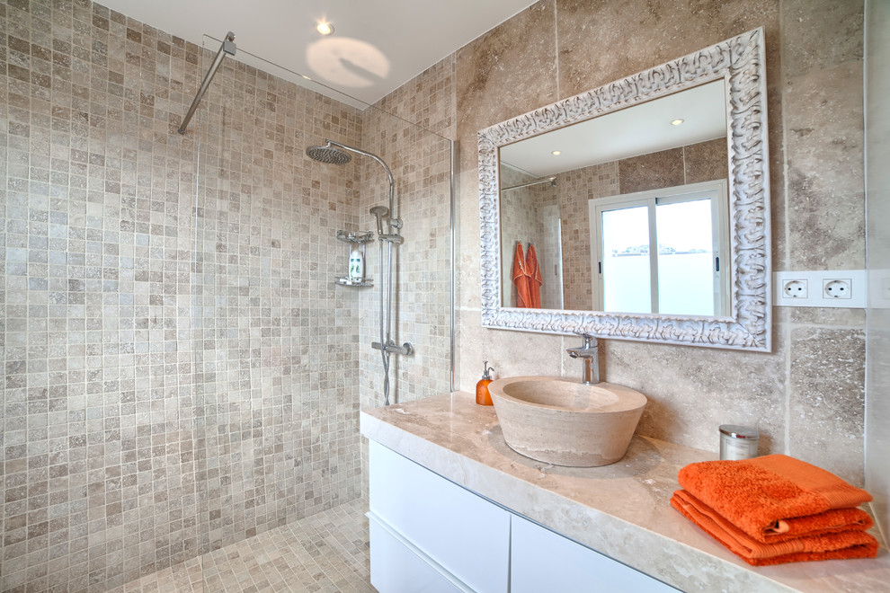 Modelo de cuarto de baño mediterráneo de tamaño medio con armarios con paneles lisos, puertas de armario blancas, ducha abierta, aseo y ducha, lavabo sobreencimera, encimera de mármol y ducha abierta