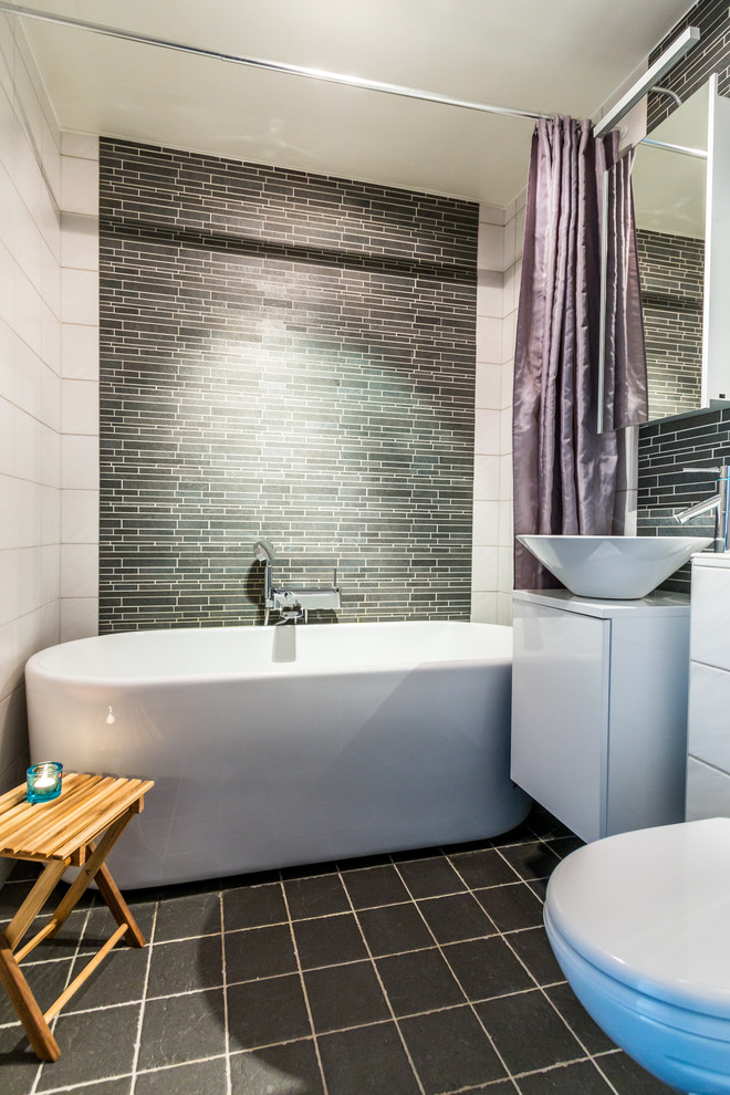 Foto på ett mellanstort funkis badrum, med släta luckor, vita skåp, ett fristående badkar, ett fristående handfat, en toalettstol med hel cisternkåpa och dusch med duschdraperi