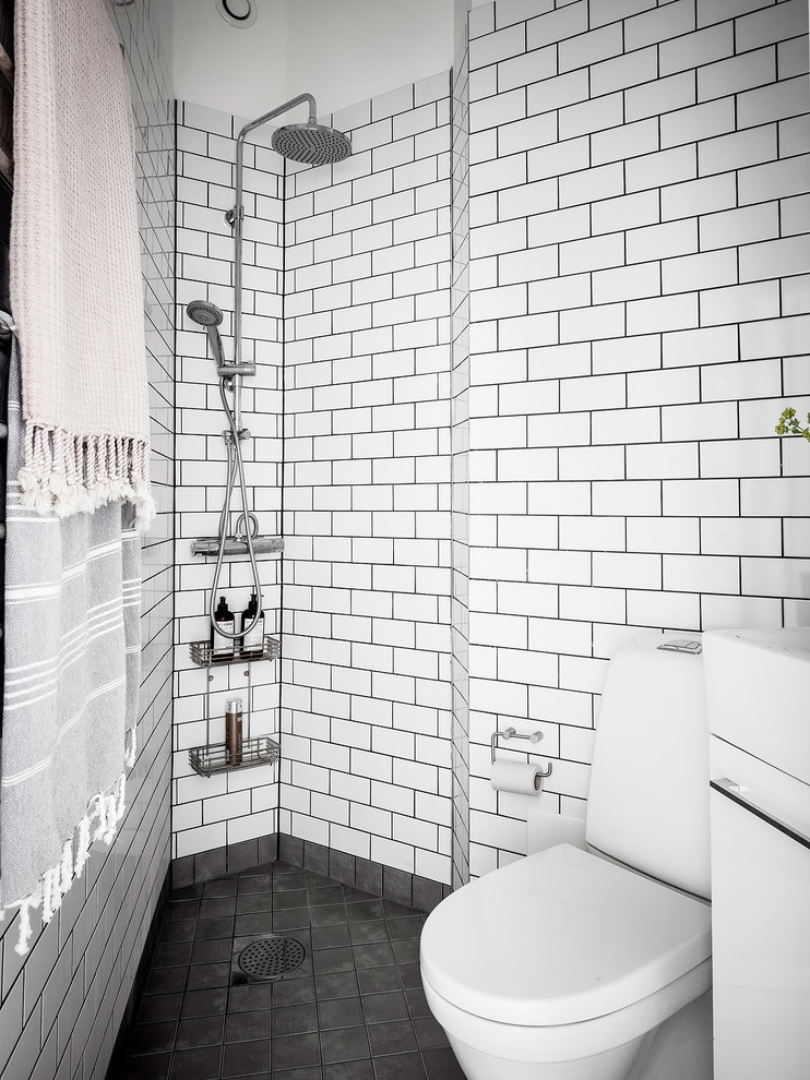 Kleines Nordisches Badezimmer mit offener Dusche, weißer Wandfarbe, schwarzem Boden, Wandtoilette mit Spülkasten, weißen Fliesen, Metrofliesen und offener Dusche in Göteborg