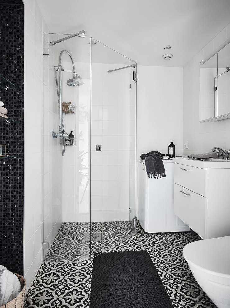 Nordisches Duschbad mit flächenbündigen Schrankfronten, weißen Schränken, Eckdusche, weißen Fliesen, weißer Wandfarbe, schwarzem Boden und Falttür-Duschabtrennung in Göteborg