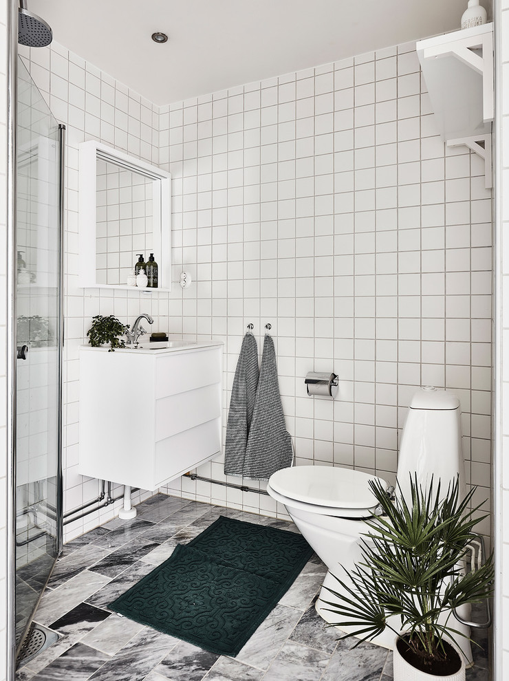 ヨーテボリにある高級な中くらいな北欧スタイルのおしゃれな浴室 (フラットパネル扉のキャビネット、白いキャビネット、コーナー設置型シャワー、一体型トイレ	、セラミックタイル、白い壁、オーバーカウンターシンク) の写真