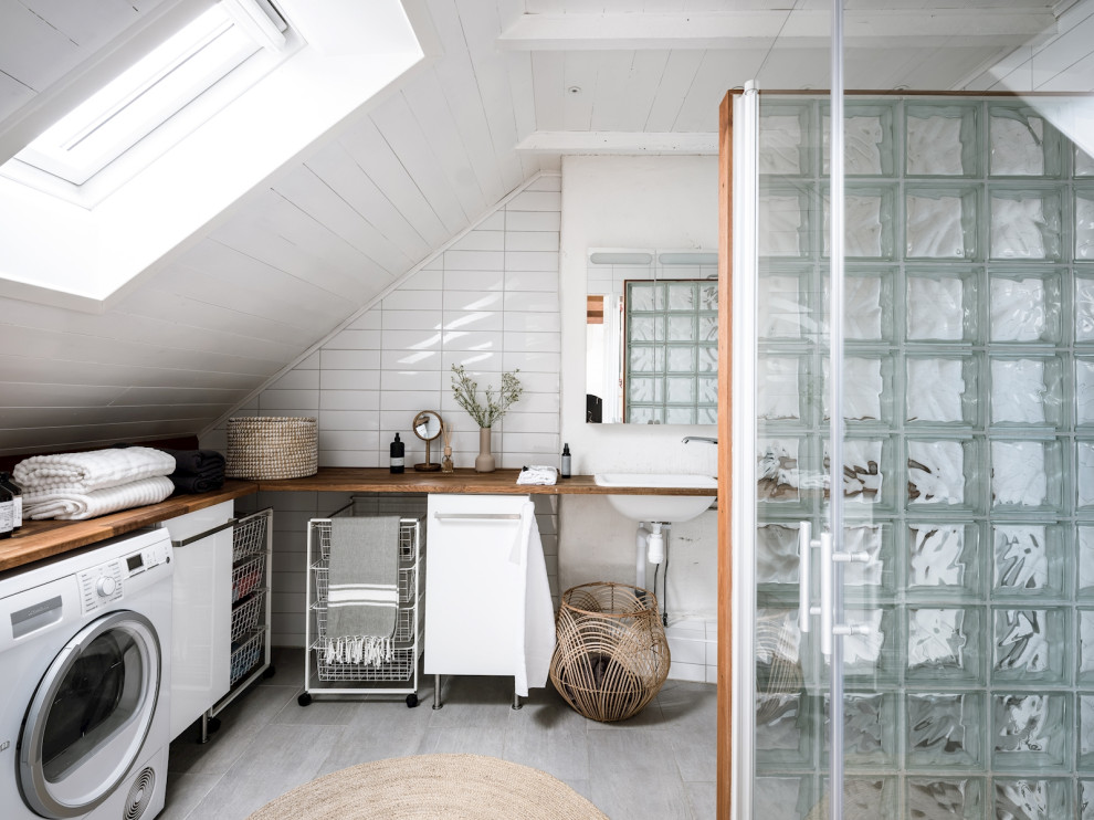 Scandinavian bathroom in Gothenburg with white tiles, white walls, a built-in sink, wooden worktops, grey floors, brown worktops, a laundry area, a single sink, a timber clad ceiling and a vaulted ceiling.