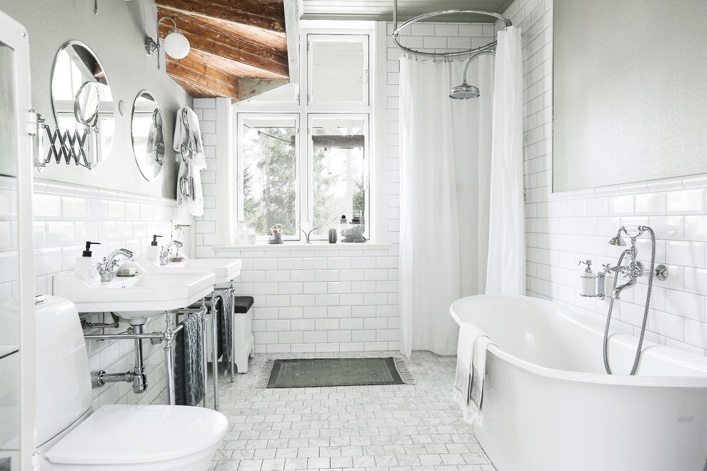 This is an example of a medium sized scandinavian shower room bathroom in Stockholm with white tiles, white walls, a freestanding bath, a walk-in shower, a two-piece toilet, metro tiles, a console sink, grey floors and a shower curtain.