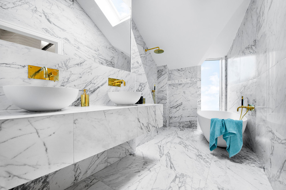 This is an example of a large contemporary bathroom in Stockholm with grey cabinets, a freestanding bath, a shower/bath combination, grey walls, marble flooring, a vessel sink and marble worktops.