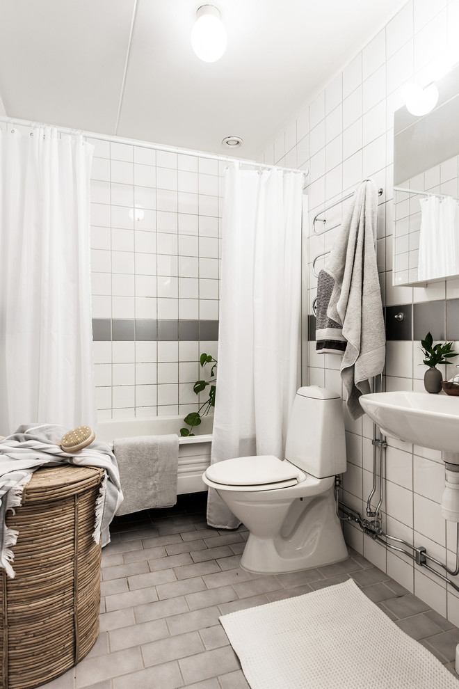 Bild på ett minimalistiskt badrum med dusch, med öppna hyllor, ett fristående badkar, en dusch/badkar-kombination, en toalettstol med separat cisternkåpa, grå kakel, vit kakel, porslinskakel, vita väggar, tegelgolv, ett väggmonterat handfat, grått golv och dusch med duschdraperi