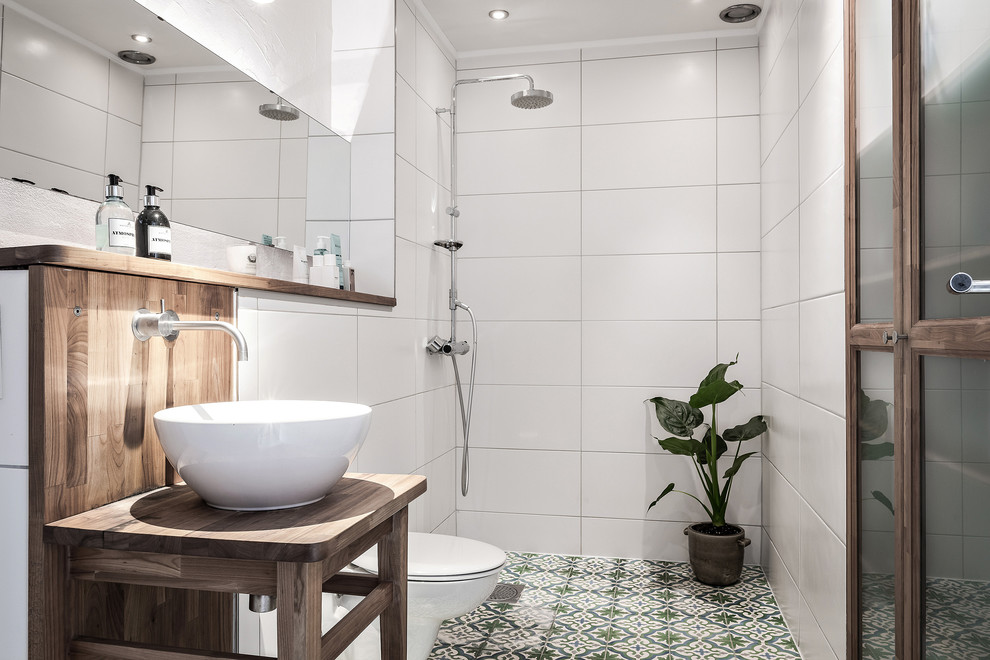 Mittelgroßes Nordisches Duschbad mit Glasfronten, dunklen Holzschränken, offener Dusche, weißen Fliesen, Zementfliesen für Boden, Aufsatzwaschbecken und buntem Boden in Göteborg