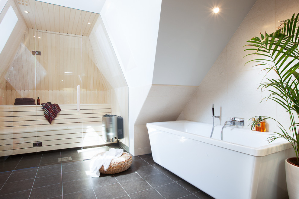 Foto di una stanza da bagno padronale nordica di medie dimensioni con vasca freestanding, pareti bianche, vasca/doccia, piastrelle grigie, piastrelle in ceramica e pavimento in pietra calcarea