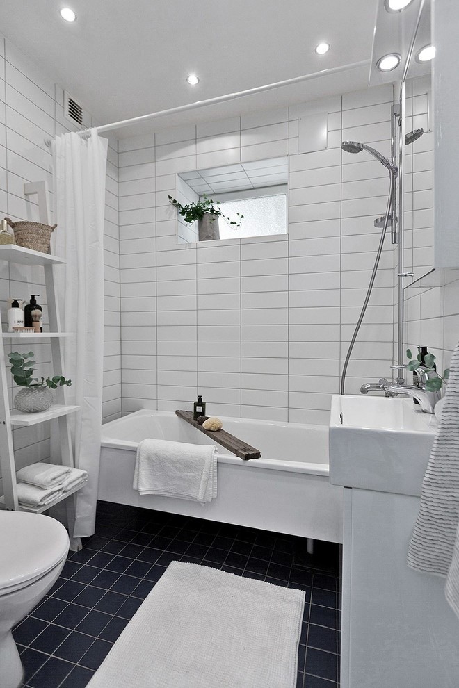 This is an example of a scandinavian shower room bathroom in Stockholm with white cabinets, an alcove bath, a shower/bath combination, white tiles, metro tiles, a console sink, black floors and a shower curtain.