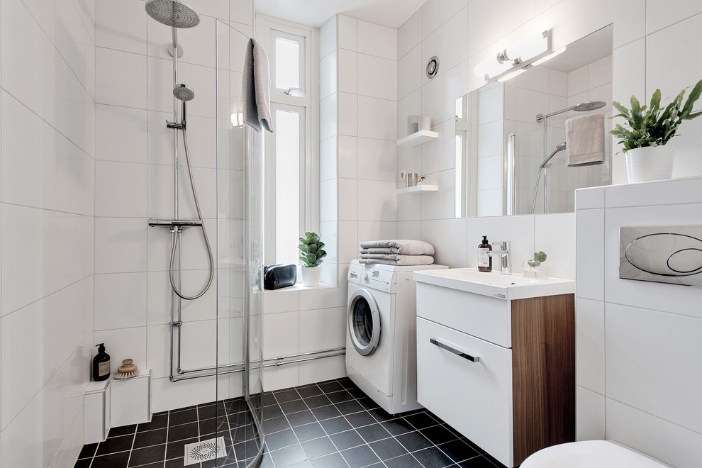 Свежая идея для дизайна: ванная комната в скандинавском стиле с плоскими фасадами, белыми фасадами, угловым душем, белой плиткой, душевой кабиной, консольной раковиной и черным полом - отличное фото интерьера