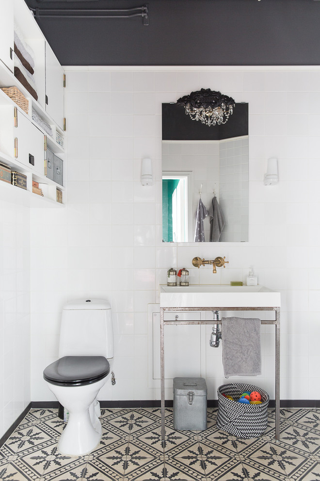 Medelhavsstil inredning av ett badrum, med en toalettstol med hel cisternkåpa, vita väggar, cementgolv och ett avlångt handfat