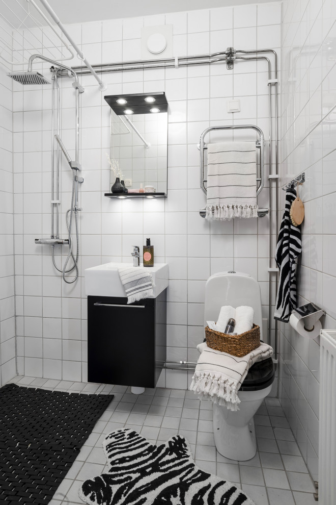 Foto de cuarto de baño único y flotante escandinavo pequeño con armarios con paneles lisos, puertas de armario negras, ducha esquinera, sanitario de una pieza, baldosas y/o azulejos blancos, aseo y ducha, lavabo integrado, suelo blanco, ducha abierta y encimeras blancas
