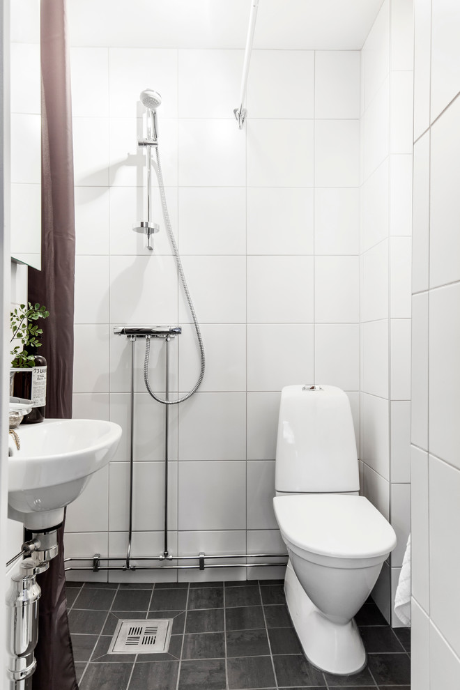 Inredning av ett skandinaviskt badrum med dusch, med en öppen dusch, vit kakel, porslinskakel, vita väggar, ett piedestal handfat, grått golv och dusch med duschdraperi