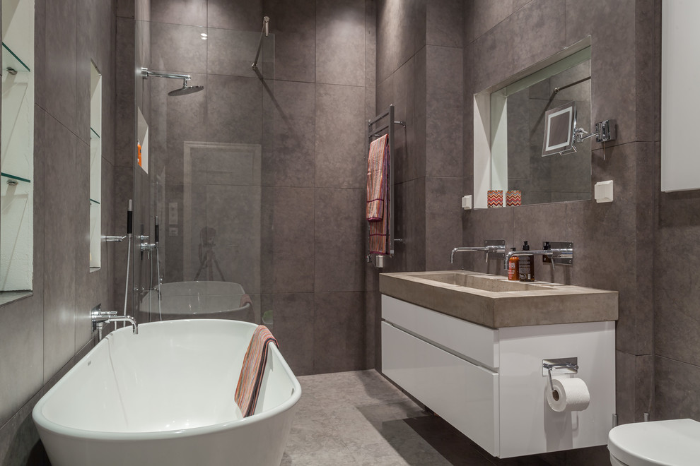 Foto på ett stort skandinaviskt en-suite badrum, med släta luckor, vita skåp, ett fristående badkar, en öppen dusch, en toalettstol med hel cisternkåpa, brun kakel, bruna väggar, ett avlångt handfat och med dusch som är öppen